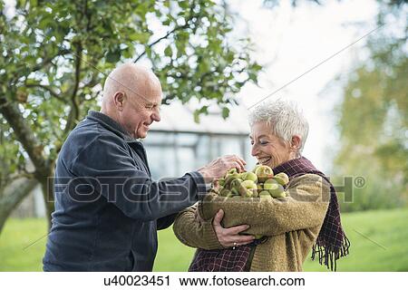 Stock Image - Portrait of happy senior couple with apples. Fotosearch
