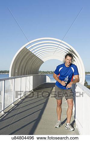 Portrait of mature male runner taking a break on footbridge View Large Photo Image Stock Photograph - Portrait of mature male runner taking a break on footbridge. Fotosearch