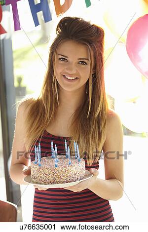 Stock Image - Portrait of teenage girl holding birthday cake. Fotosearch