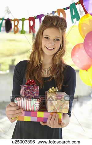Stock Photograph - Portrait of teenage girl holding birthday gifts. Fotosearch