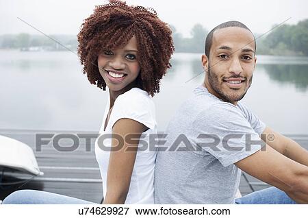 Portrait of young couple smiling, back to back View Large Photo Image Stock Photo - Portrait of young couple smiling, back to back. Fotosearch
