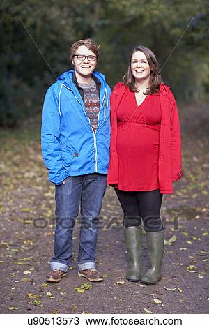 Stock Image - Portrait of young couple walking in woods. Fotosearch
