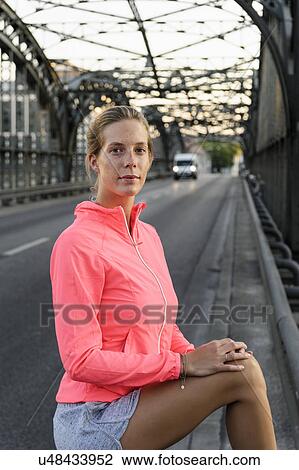 Stock Image - Portrait of young female runner on bridge. Fotosearch