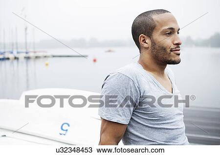 Stock Image - Portrait of young man by lake. Fotosearch