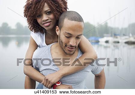 Portrait of young man giving woman piggyback View Large Photo Image Stock Image - Portrait of young man giving woman piggyback. Fotosearch