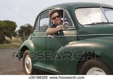 Stock Photo - Portrait of young man in vintage morris minor. Fotosearch