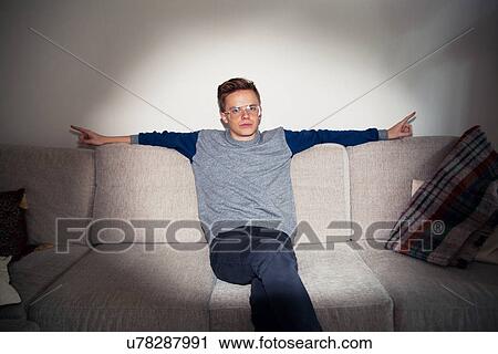 Stock Image - Portrait of young man relaxing on sofa in spotlight. Fotosearch