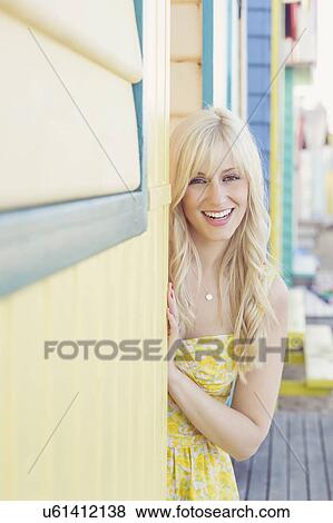 Stock Photo - Portrait of young woman next to beach huts. Fotosearch