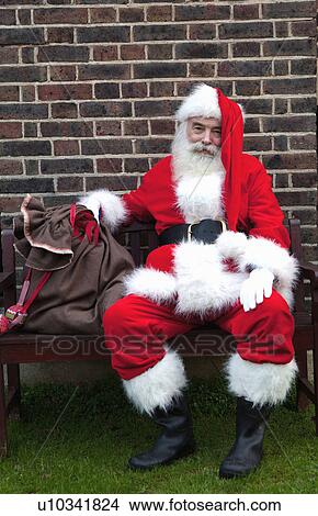 Picture - Santa Claus taking break on bench. Fotosearch