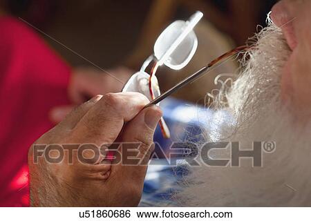 Stock Photograph - Senior man chewing end of spectacles. Fotosearch