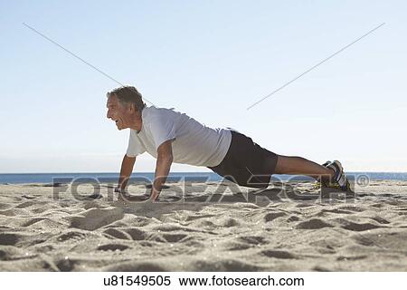 Stock Photography - Senior man doing push ups on beach. Fotosearch