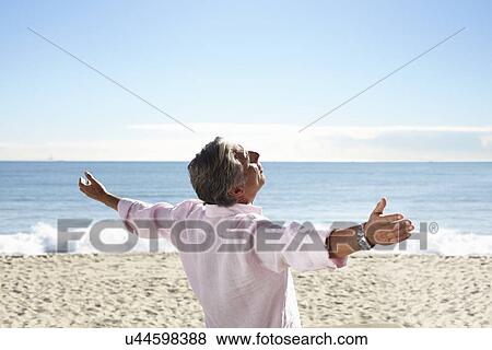 Stock Photo - Senior man on beach with arms outspread. Fotosearch