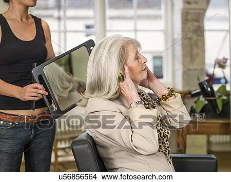 Picture - Senior woman admiring hairstyle at hairdressers. Fotosearch