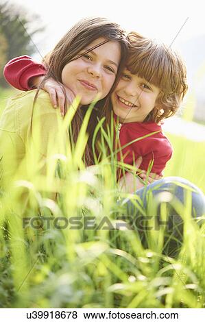 Sister and younger brother sitting in grassy field View Large Photo Image Stock Photo - Sister and younger brother sitting in grassy field. Fotosearch