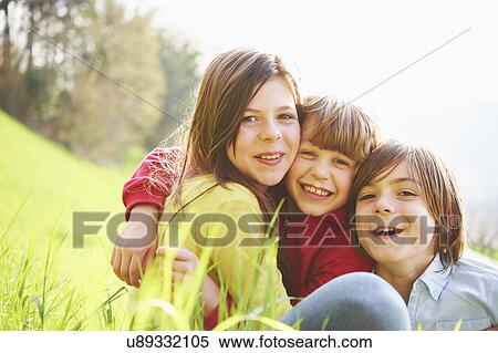 Sister and younger brothers sitting in grassy field View Large Photo Image Stock Photography - Sister and younger brothers sitting in grassy field. Fotosearch