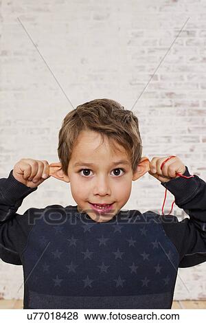 Stock Photo - Studio portrait of boy pulling his ears. Fotosearch