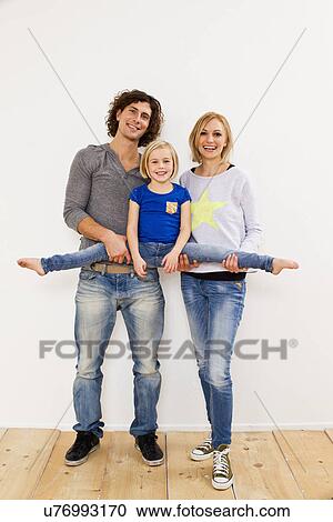Stock Image - Studio portrait of couple holding up daughter. Fotosearch