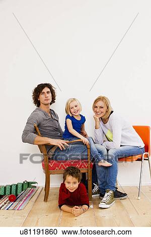 Stock Image - Studio portrait of couple sitting with son and daughter. Fotosearch