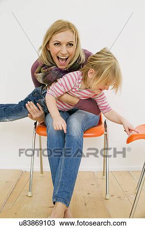 Stock Image - Studio portrait of mother holding up young daughter. Fotosearch