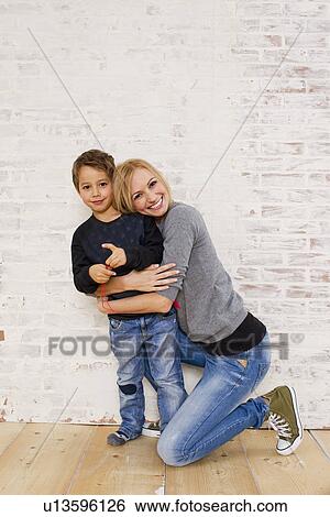 Stock Photograph - Studio portrait of mother kneeling next to son. Fotosearch