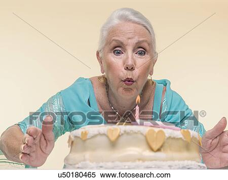 Studio portrait of senior woman blowing out birthday candle View Large Photo Image Stock Photography - Studio portrait of senior woman blowing out birthday candle. Fotosearch