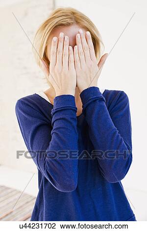 Studio portrait of young woman hiding behind hands View Large Photo Image Stock Image - Studio portrait of young woman hiding behind hands. Fotosearch