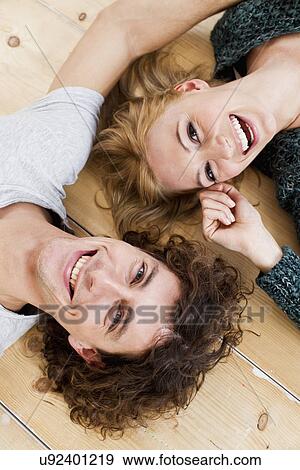 Stock Photo - Studio shot couple lying on floor. Fotosearch