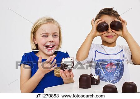 Stock Image - Studio shot of brother and sister with chocolate marshmallows. Fotosearch