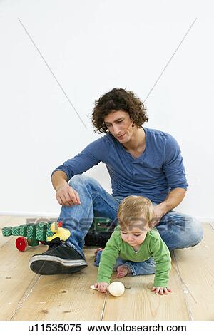 Stock Photography - Studio shot of father and baby daughter paying on floor. Fotosearch