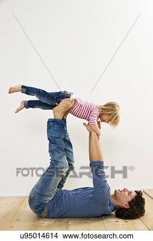 Studio shot of father lifting up daughter whilst lying on back View Large Photo Image Picture - Studio shot of father lifting up daughter whilst lying on back. Fotosearch