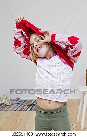 Studio shot of girl pulling off red heart sweater View Large Photo Image Stock Image - Studio shot of girl pulling off red heart sweater. Fotosearch