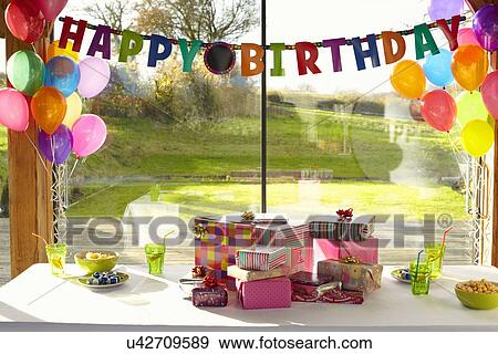 Stock Photo - Table laid with birthday gifts and balloons. Fotosearch