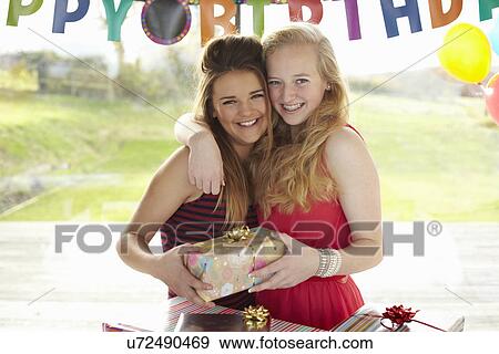 Stock Photo - Teenage girl and friend with birthday gift. Fotosearch