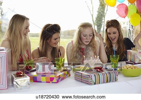 Stock Image - Teenage girl blowing out birthday candles with friends. Fotosearch