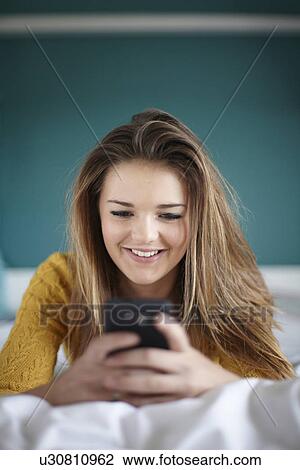 Teenage girl in bedroom texting on smartphone View Large Photo Image Stock Image - Teenage girl in bedroom texting on smartphone. Fotosearch