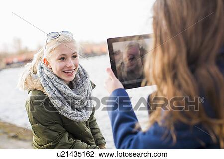 Teenage girl photographing friend with digital tablet View Large Photo Image Stock Image - Teenage girl photographing friend with digital tablet. Fotosearch