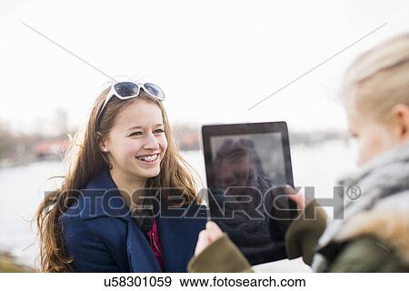 Teenage girl photographing friend with digital tablet View Large Photo Image Stock Photo - Teenage girl photographing friend with digital tablet. Fotosearch