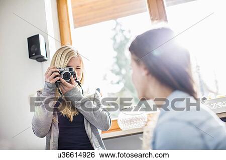 Teenage girl photographing friend with camera View Large Photo Image Stock Photograph - Teenage girl photographing friend with camera. Fotosearch