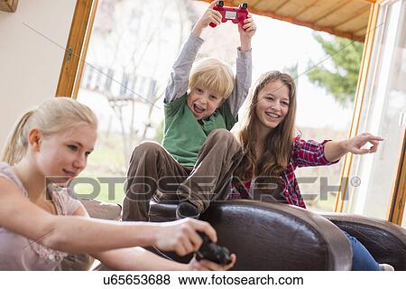 Stock Photo - Teenage girls and boy playing games console. Fotosearch