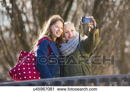 Teenage girls photographing themselves with camera View Large Photo Image Stock Image - Teenage girls photographing themselves with camera. Fotosearch