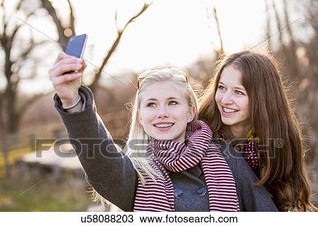 Teenage girls photographing themselves with smartphone View Large Photo Image Stock Image - Teenage girls photographing themselves with smartphone. Fotosearch