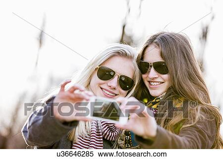 Stock Photography - Teenage girls photographing themselves with smartphone. Fotosearch