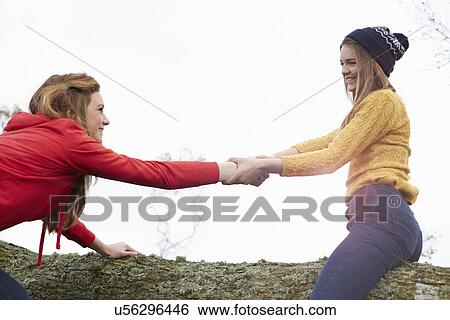 Teenage girls play fighting on tree trunk View Large Photo Image Stock Photograph - Teenage girls play fighting on tree trunk. Fotosearch