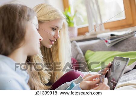 Stock Photo - Teenage girls using tablet for online shopping. Fotosearch
