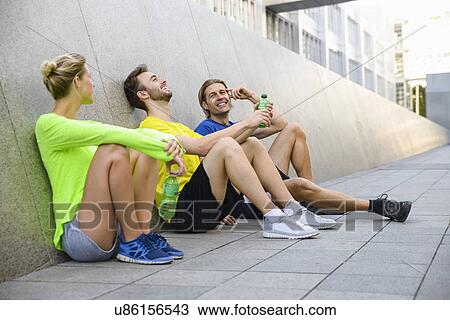 Three friends sitting on floor wearing sports clothing View Large Photo Image Stock Image - Three friends sitting on floor wearing sports clothing. Fotosearch