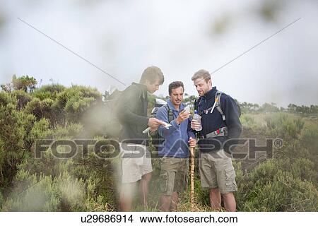 Three male hikers looking at smartphone View Large Photo Image Picture - Three male hikers looking at smartphone. Fotosearch