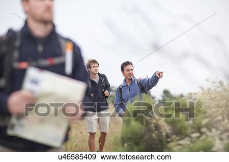 Stock Photo - Three male hikers with backpacks and map. Fotosearch