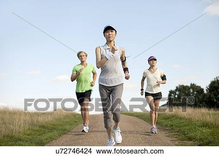 Three young adults jogging along field track View Large Photo Image Picture - Three young adults jogging along field track. Fotosearch