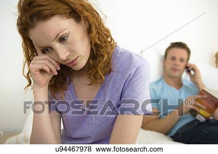 Stock Photo - Troubled woman, husband in background. Fotosearch