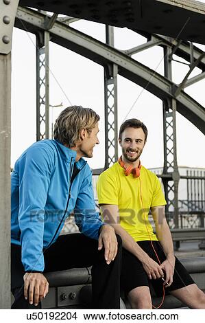 Picture - Two male runners chatting on bridge. Fotosearch